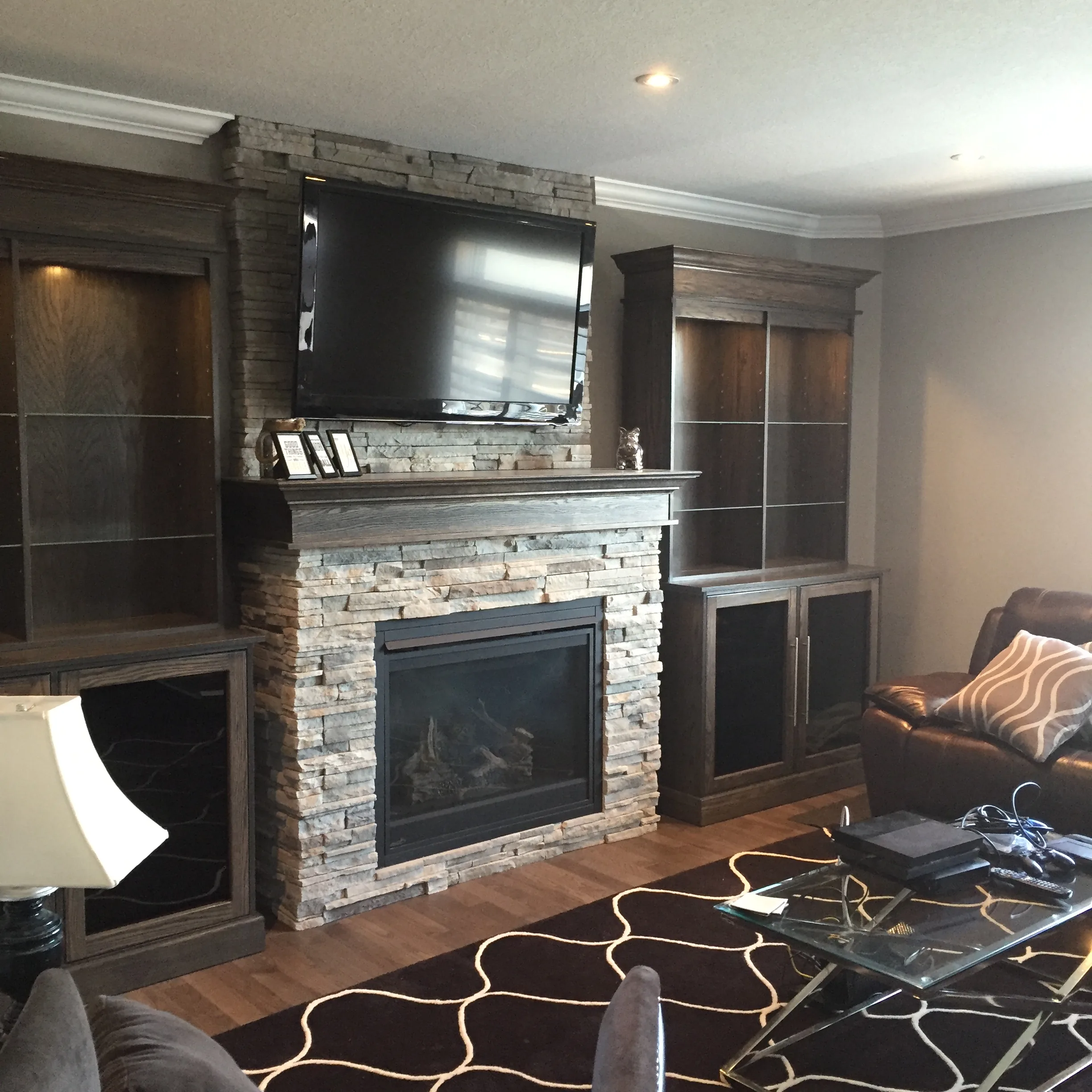 Dark stacked-stone fireplace with dark wood built-in bookcases