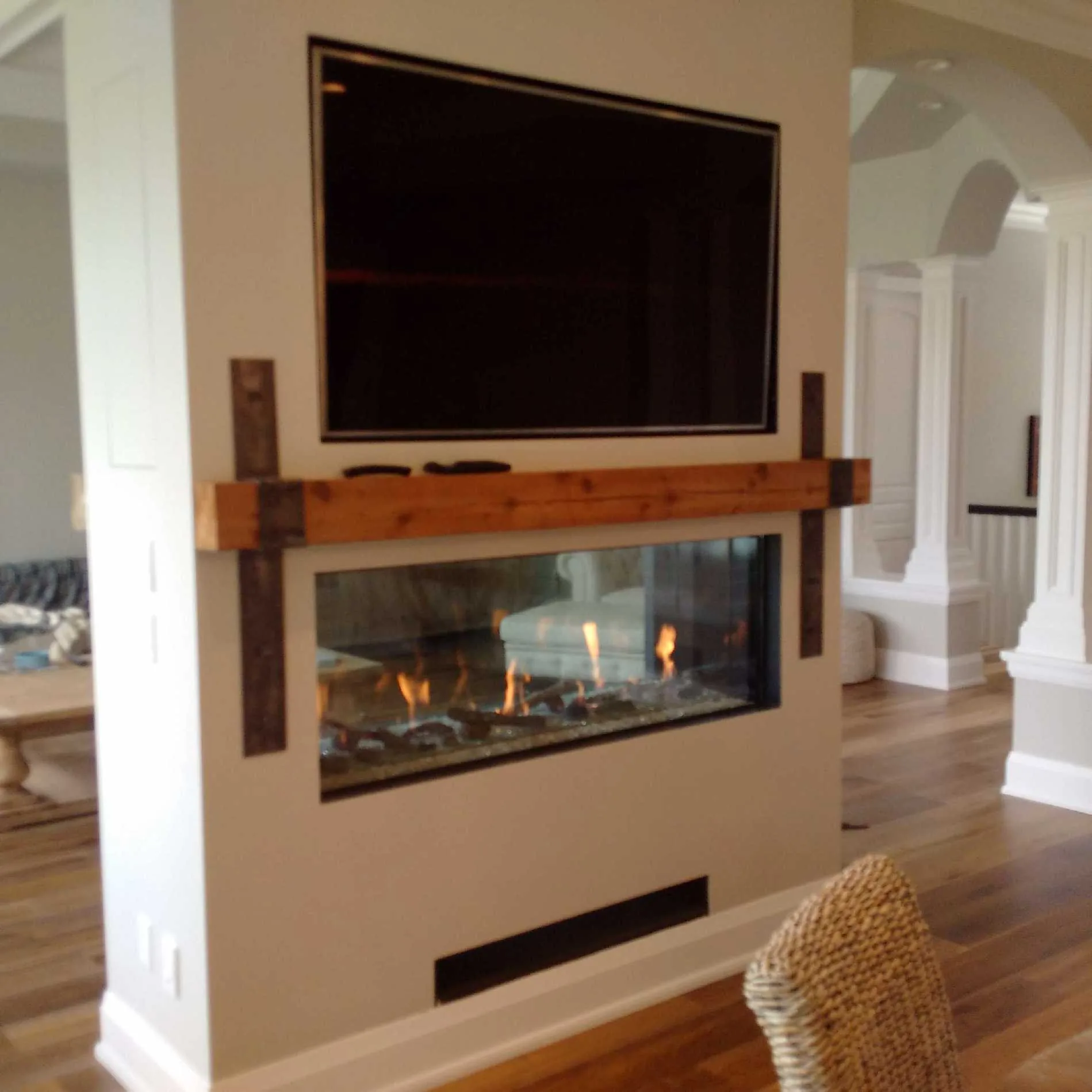 Traditional fireplace with TV mount and rustic wood mantel accented with iron straps