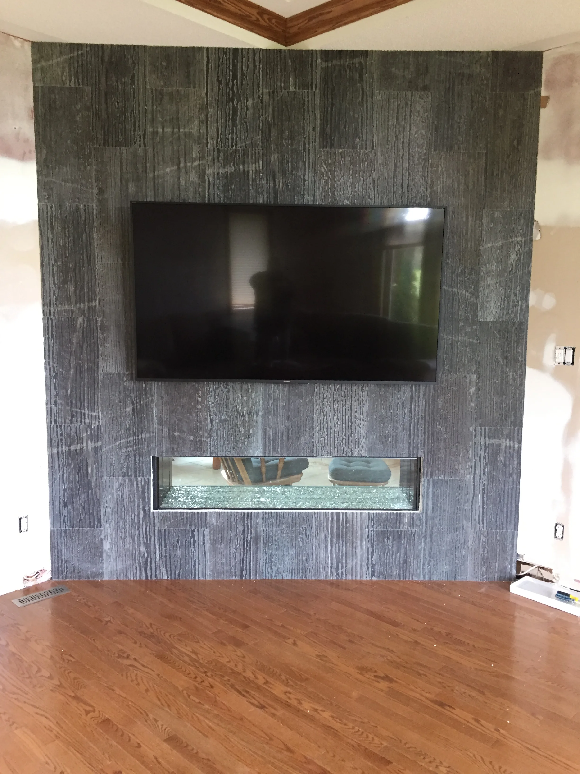 Charcoal linear tile fireplace wall with narrow vertical insert and mounted TV