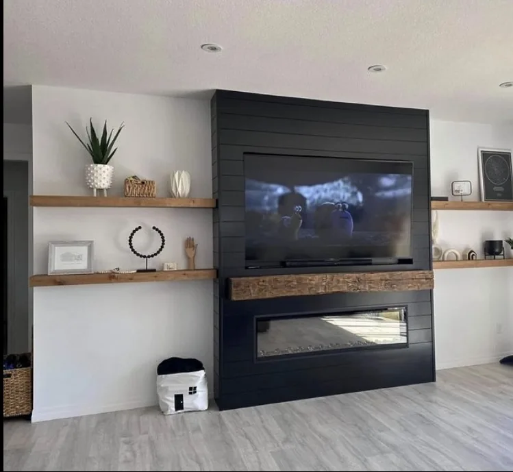 Black shiplap fireplace with reclaimed timber mantel, TV, and floating wood shelves