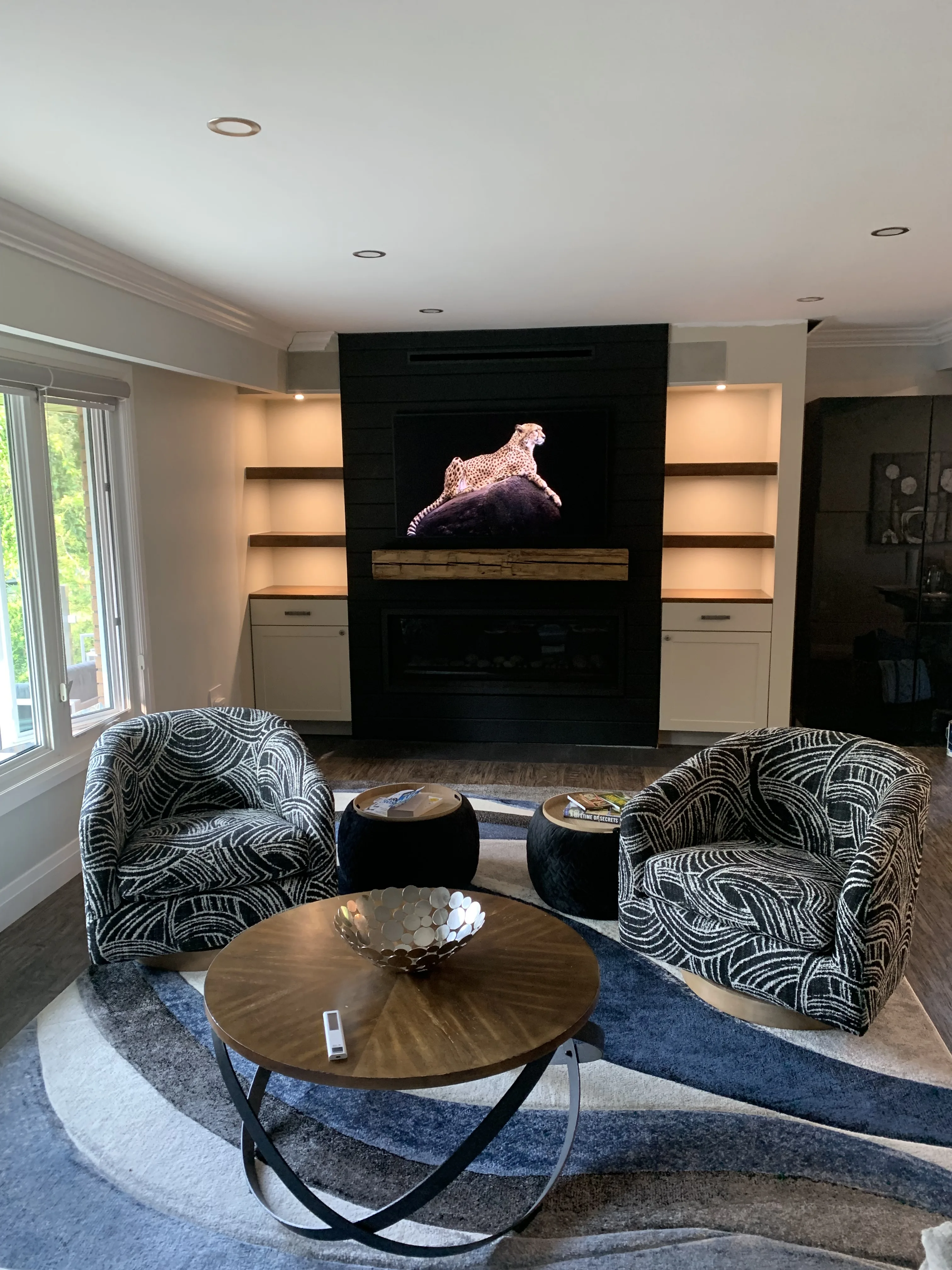 Black cabinet fireplace with sculpted art, warm interior lighting, and blue armchairs