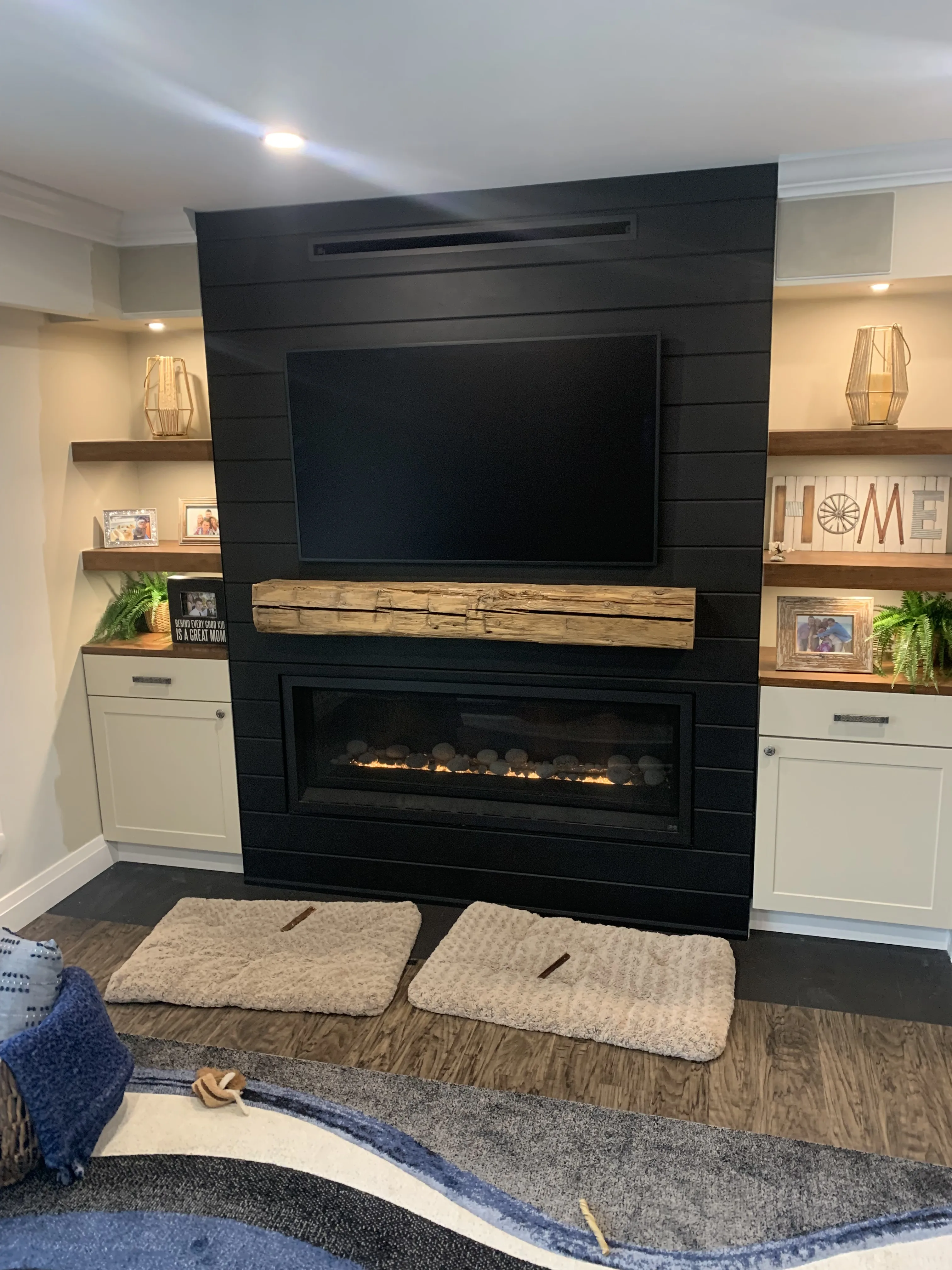 Black shiplap fireplace with reclaimed timber mantel and TV over linear insert